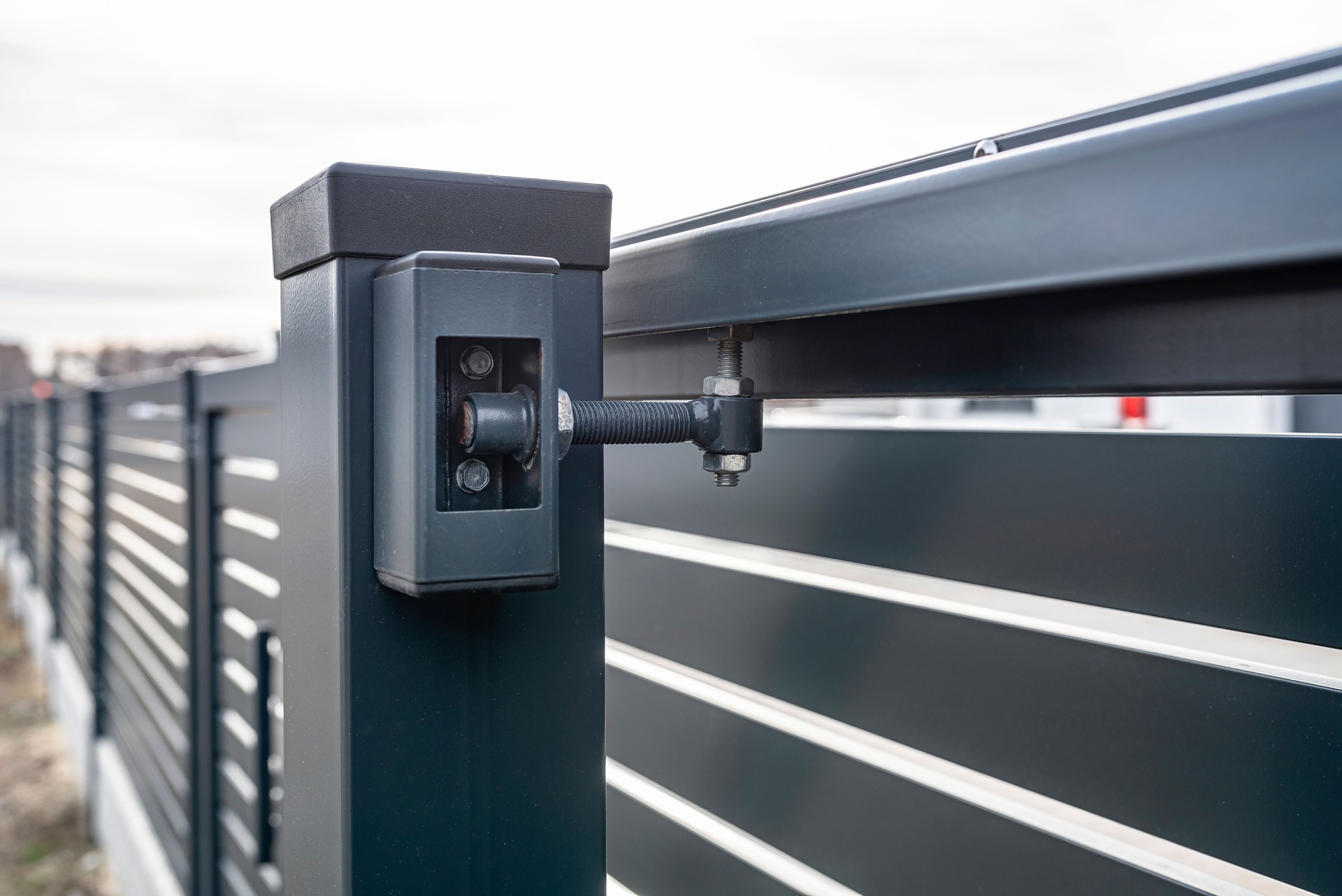 Modern sliding entrance gate in anthracite color, visible upper guide rollers.